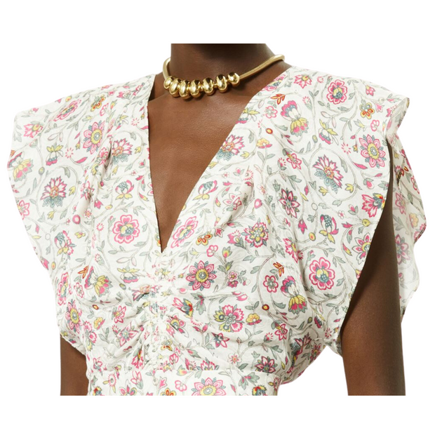 Modeled side view of a sleeveless ecru pattern top. The top is ruched through the waist with a band and is styled with a chunky gold necklace. The image is shown from chin to hip, capturing the side view, against a white background.