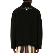 Image: A back view of an oversized black turtleneck sweater, showcasing a metal detail on the back.